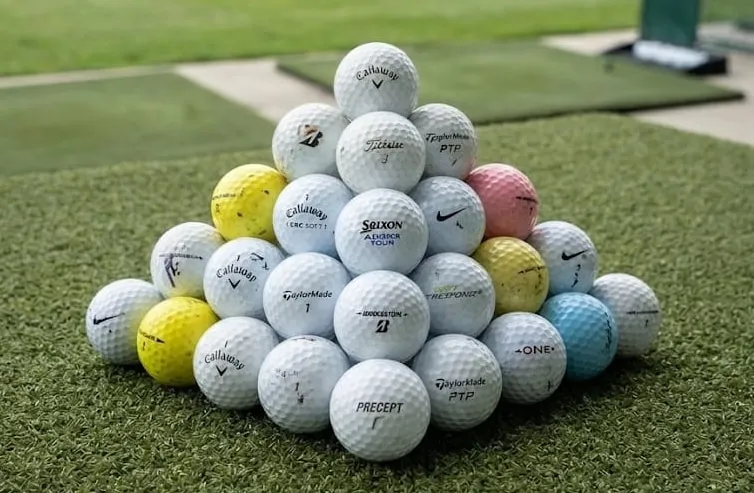 Pirámide de bolas de marcas, modelos y colores mezclados sobre el césped de un campo de prácticas
